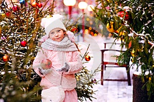 christmas portrait of happy child girl walking outdoor, snowy winter decorated trees on background.