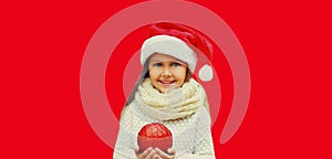 Christmas portrait of happy smiling little girl child in red santa hat with ball toy isolated on studio background