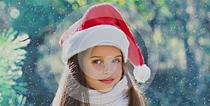 Christmas portrait happy smiling little girl child in santa red hat outdoors