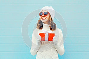 Christmas portrait happy smiling woman with gift box wearing a knitted hat sweater over blue