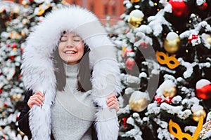 Christmas portrait of happy young woman walking in winter snowy city