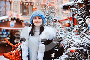 Christmas portrait of happy young woman walking in winter snowy city