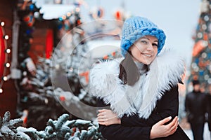 Christmas portrait of happy young woman walking in winter snowy city