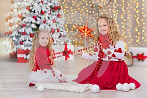 Christmas portrait of two beautyful cute girls Smiling sisters friends and xmas luxury green white tree in unique interior studio
