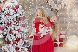 Christmas portrait of two beautyful cute girls Smiling sisters friends and xmas luxury green white tree in unique interior studio