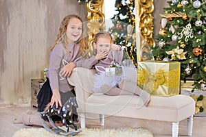 Christmas portrait of two beautyful cute girls Smiling sisters friends and xmas luxury green white tree in unique interior studio