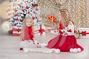 Christmas portrait of two beautyful cute girls Smiling sisters friends and xmas luxury green white tree in unique interior studio