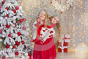 Christmas portrait of two beautyful cute girls Smiling sisters friends and xmas luxury green white tree in unique interior studio