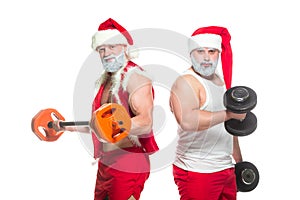 Christmas. Portrait of two strong muscular bearded athletes in Santa Claus costumes, training by lifting barbells