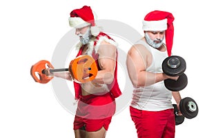 Christmas. Portrait of two strong muscular bearded athletes in Santa Claus costumes, training by lifting barbells