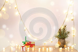 Christmas poster mock up. Green fir branches red craft paper gift boxes lights garland white background