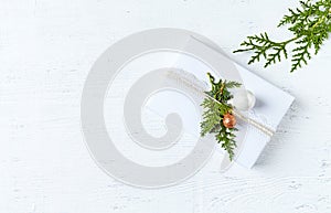 Christmas present decorated with evergreen twigs on white background. Flat lay. Copy space
