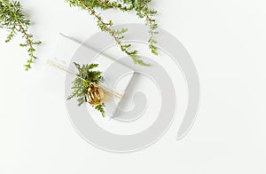 Christmas present decorated with evergreen twigs on white background. Flatlay. Copy space