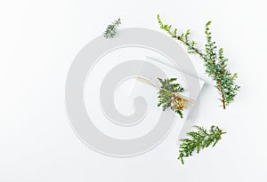 Christmas present decorated with evergreen twigs on white background. Flatlay. Copy space