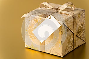 Christmas present with gold ribbon and blank tag