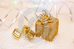 Christmas present in gold wrapping with ribbon on winter background