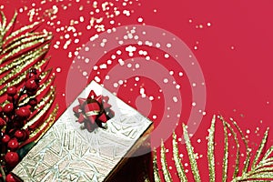 Christmas present in a golden box on red background. Valentines day gift.