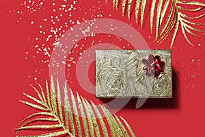 Christmas present in a golden box on red background. Valentines day gift.