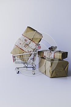 Christmas present inside a miniature shopping cart surrounded by more gifts