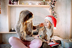 Christmas presents for children. in bright guest house on the bed happy family mother and baby child daughter write a letter to