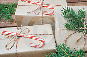 Christmas presents or gift box wrapped in kraft paper with decorations and fir branch on rustic wooden background.