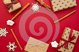 Christmas presents. Gifts packed in craft paper, decorative snowflakes, twine, cinnamon sticks on red background. Xmas and Happy N