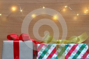 Christmas presents on wooden background with lights.