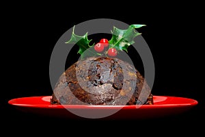 Christmas pudding with holly isolated on black