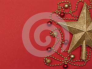 Christmas red background with golden star - the top of Christmas tree, golden beads and Christmas decoration.