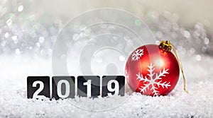 Christmas red ball and new year 2019, on snow, abstract bokeh lights background