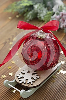 Christmas red bauble on sleigh with red ribbon bow, on wooden rustic table. Copy space