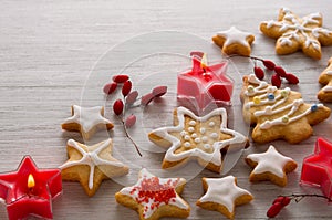 Christmas red berry fruit, home made cookies in shape of star and tree with icing on white wooden background, copy space for text