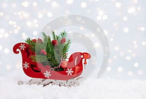 Christmas red sleigh with fir branches in the snow on a winter background. New Year greeting card with copy space