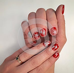 Christmas red women's manicure. Nails with red gel polish and Christmas silver snowflakes and decorations design