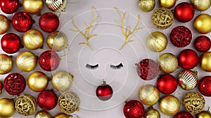 Christmas reindeer blinking with eye lashes surrounded with shiny gold and red Christmas ornaments. Stop motion