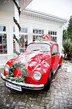 Christmas retro red car with present boxes on top. White house on background