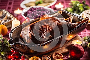 Christmas roast goose with red cabbage, potato dumplings in an original baking dish on the festive table