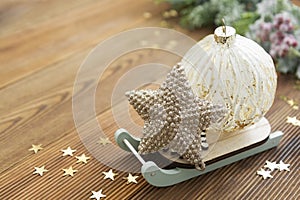 Christmas rustic background. Golden bauble with golden ribbon and winter decoration over wooden table, copy space