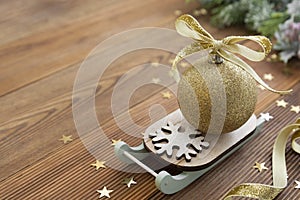 Christmas rustic background. Golden bauble with golden ribbon and winter decoration over wooden table, copy space