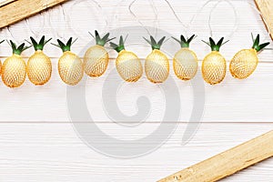 Christmas rustic background with string lights as pineapples golden colored. Festive decoration, New Year fairy garland