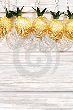 Christmas rustic background with string lights as pineapples golden colored. Festive decoration, New Year fairy garland.