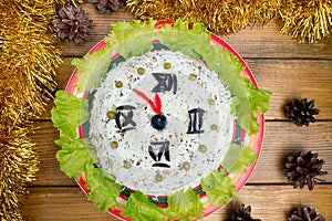 The Christmas salad rice olives greens peas - concept New year clock face, midnight, brown wooden background spruce