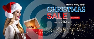 Christmas sale message with woman opening a gift box