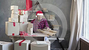 Christmas sale and small business, Caucasian man sits at the table in his home office and prepares goods for the mandrel