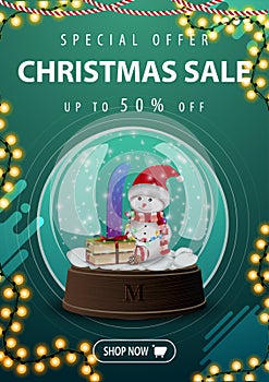 Christmas sale, up to 50% off, vertical green discount banner with garland and snow globe with snowman