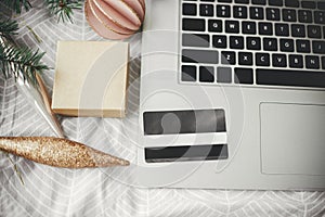 Christmas Sales and shopping online.Credit card on laptop on background of stylish bed with modern christmas ornaments and gift.