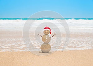 Christmas sandy snowman in santa hat at tropical beach