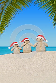 Christmas sandy Snowmen family in Santa hats at palm beach