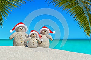 Piesočnatý snehuliaci rodina v klobúky na palma pláž 