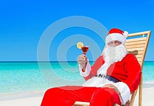Christmas Santa Claus with cocktail on sunlounger at tropical be
